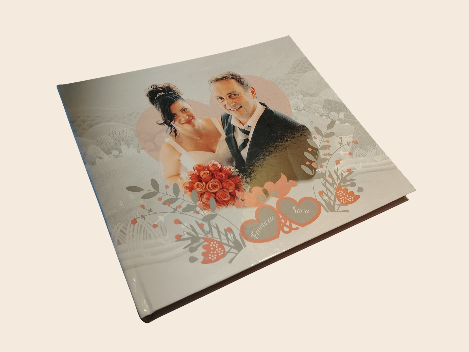 Copertina di un fotolibro matrimonio d’autore: ritratto degli sposi, decori floreali e nomi in copertina lucida